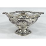 An elongated oval bowl on pedestal with scroll and flower border, extensively pierced body with