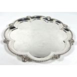 A hallmarked silver scalloped circular tray with raised beaded border and sunburst facemask