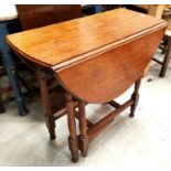 An oak dining table with oval drop leaf top, on turned legs