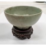A Chinese celadon glazed bowl with foot on associated hardwood stand diameter 9.5cm