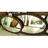 Two bevelled edge wall mirrors in oval mahogany frames