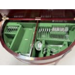 A 12 setting canteen of silver plated cutlery housed in demi-lune mahogany table / cabinet