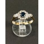 An 18ct hallmarked gold ring with central sapphire and small diamonds in crossover form