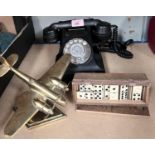 A brass aeroplane desk weight, a vintage Bakelite rotary telephone and a set of dominoes