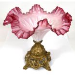 A late 19th/early 20th century table centre in folded cranberry glass on gilt metal base