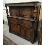 A 1930's carved oak court cupboard in the Jacobean style with twin cupboards over 2 drawers and