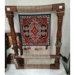 A display item depicting a traditional loom set up with small tools attached, ht 55 x 40cm