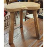 An oak milking stool by Thompson Kilburn Mouseman with saddle seat and 3 legs