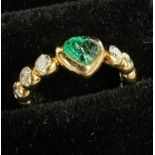 An 18 carat hallmarked gold ring set heart shaped cabochon emerald flanked by 3 brilliant cut