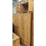 A modern pine triple wardrobe, kneehole dressing table and pair of bedside cabinets