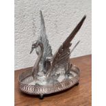 A silver plated swan shaped bandy warmer with central light.