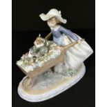 A Lladro 'Barrow of Fun' figure - girl pushing a wheelbarrow with 2 puppies, length 23cm (a couple