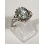 A white metal ring set with pale oval aquamarine colour stone surrounded by diamond chips, 2.7gm