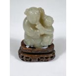 A Chinese jade coloured hardstone figure of adult and child on hard wood stand, ht. 5cm