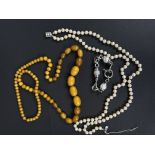 A composition orange amber coloured necklace formed from graduating round and oval beads, largest