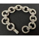 A white metal bracelet formed from circular filigree links