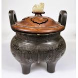 A Chinese bronze censer with 2 large hoops and fitted pierced wooden lid with jade finial, on 3