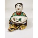 A Chinese ceramic polychrome figure of seated girl holding very large oyster shell decorated with