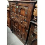 A Jacobean style carved oak drinks cabinet with fall front over drawer and double cupboard