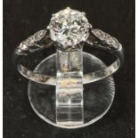 A diamond solitaire ring with 3 smaller diamonds to each shoulder, stamped 'plat', central stone 0.