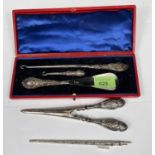 A cased 3 piece set of shoehorn, boot & button hook with embossed handles; a similar pair of glove