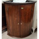 An 18th century Georgian bow front corner cupboard in crossbanded mahogany with moulded cornice,