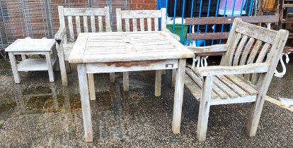 A teak garden set table and three chairs plus covers