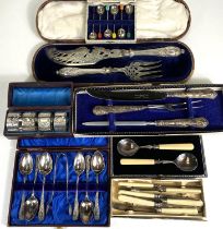 A silver handled boxed carving set, four cased silver plated buckle napkin rings; a cased set of