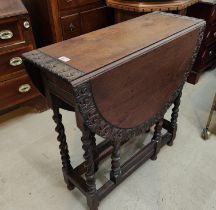 A carved oak dining table with drop leaf top