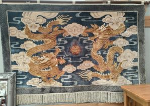 A 20th Chinese wall hanging depicting two yellow five clawed dragons on blue back