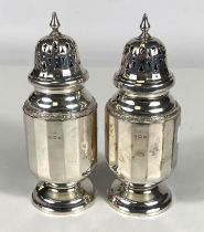 A hallmarked silver pair of sugar dredgers in the Georgian style with pierced domed tops and