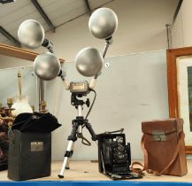 A GRAIL travelling lamp, a Mobilite photo spotlight, a Goerz folding camera with plates