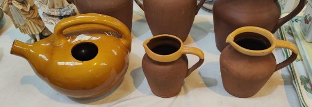 Two vintage terracotta milk jugs with yellow rims and an unusual wine pot in yellow glaze