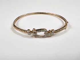 A 9ct hallmarked gold hinged bangle with horseshoe shaped mount set with small diamonds 5.7gm