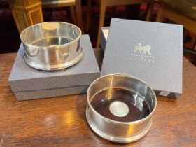 Two boxed silver wine coasters