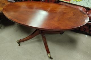 An inlaid oval reproduction coffee table on four splay feet with brass casters in the 'Reprodoux'