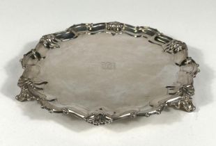 A hallmarked silver circular salver in the Georgian style with scroll and shell border, London 1926,