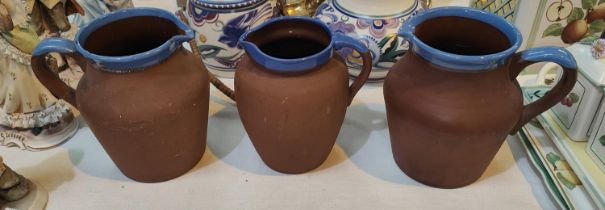 Three vintage terracotta milk jugs with blue rims