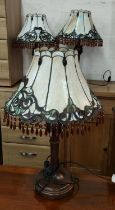 A set of 3 bronzed table lamps with Tiffany style leaded and coloured glass light shades.