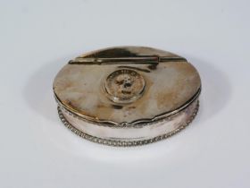 A 19th century oval white metal snuff box with 1806 coin top, hinged lid and piecrust border