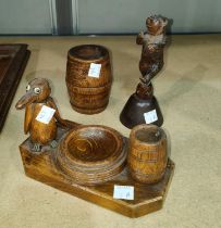 A Black Forrest carved bell in the form of a dancing bear, a carved wooden ink well and a similar