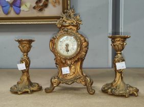 A Rococo style garniture gilt clock with decorative and enamelled dial and candle holders