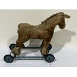 An early 20th century Chiltern Toys gold plush push-along horse. 19' high. Distressed.