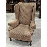 A 1920s upholstered wing armchair on cabriole legs