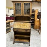 An Arts and Crafts oak bureau bookcase, enclosed by a pair of leaded glazed doors. 31½'w x 72'h.