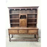 A George III style oak dresser, the raised rack with cupboard and shelves flanking. Of recent