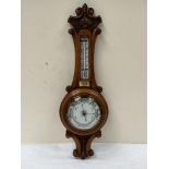 A Victorian oak carved aneroid barometer with thermometer scale. 24' high