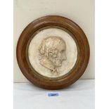 A 19th century plaster relief plaque depicting a lady's head in profile. The oak frame. 11¼' diam.