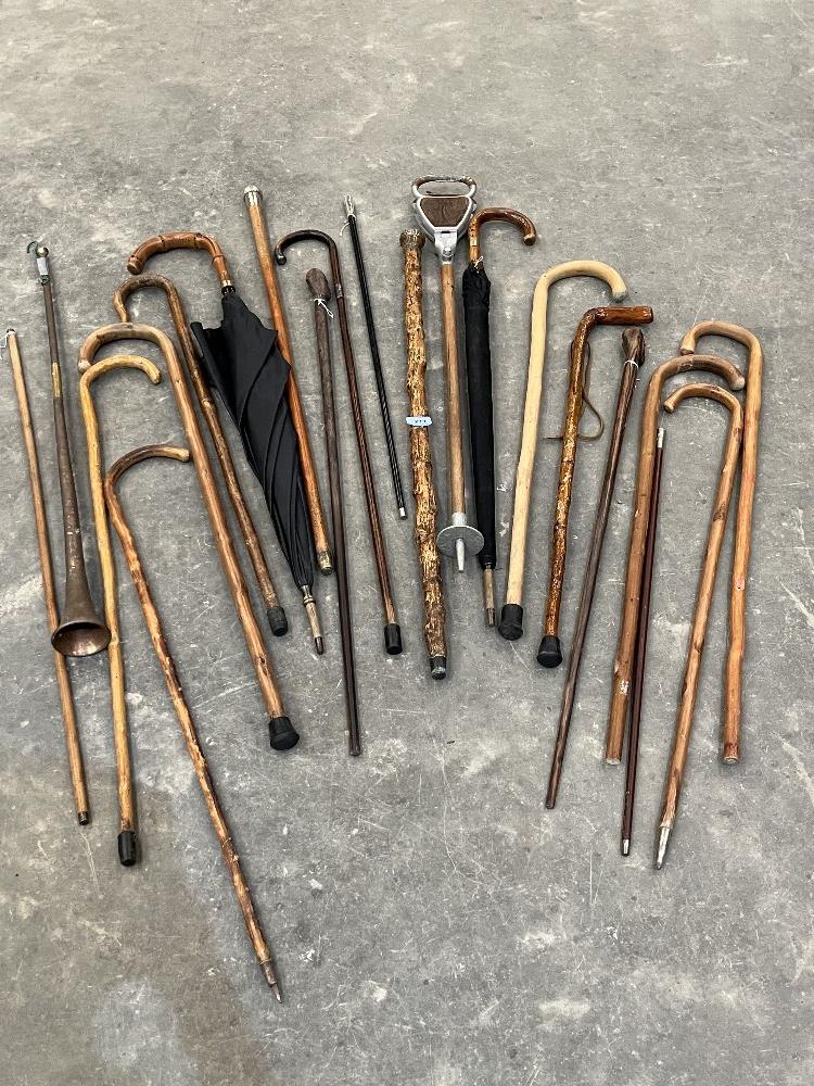 A collection of walking sticks, canes, umbrellas etc. including three with silver pommels or collars