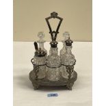 A plated cruet frame with five cut glass bottles and a jar. 11' high